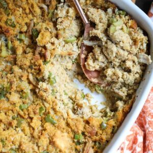 southern cornbread dressing in a white baking dish with an orange and white linen underneath.