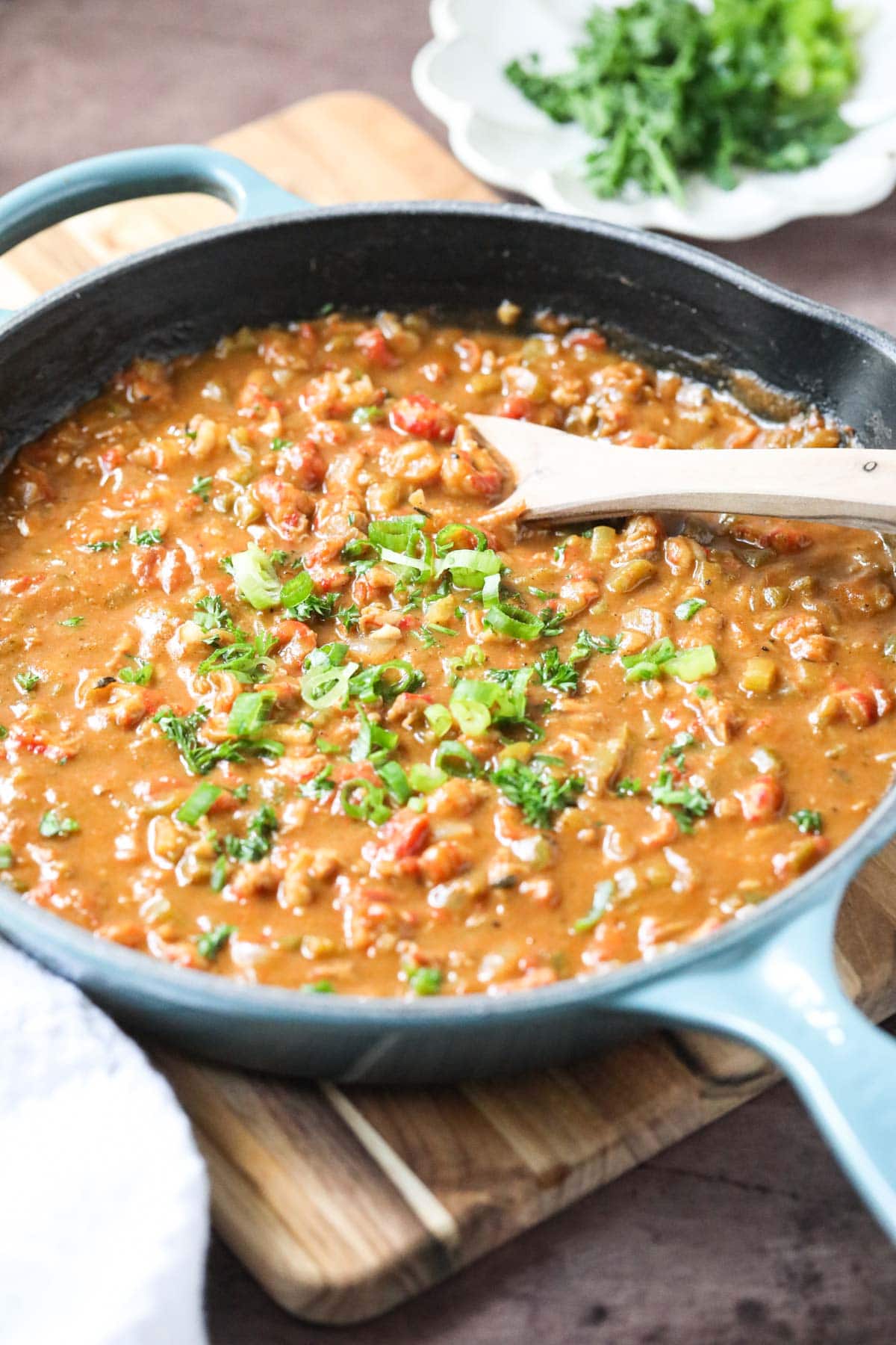 crawfish etouffee in a cast iron skillet with a wooden spoon.