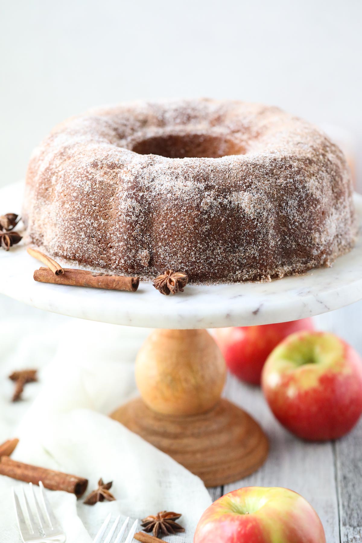 apple cider donut cake on a wooden cake stand.