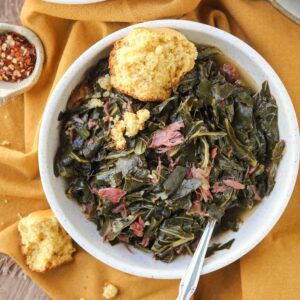 southern collard greens in a white bowl with cornbread.