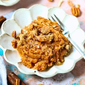 A serving of sweet potato casserole with pecans crumble on a dessert plate.