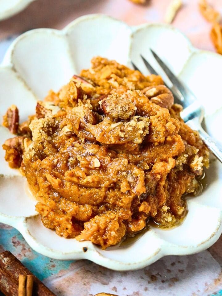 A serving of sweet potato casserole with pecans crumble on a dessert plate.