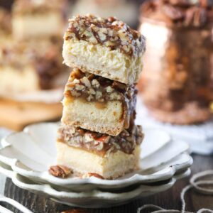 pecan pie cheesecake bars stacked on a white plate.
