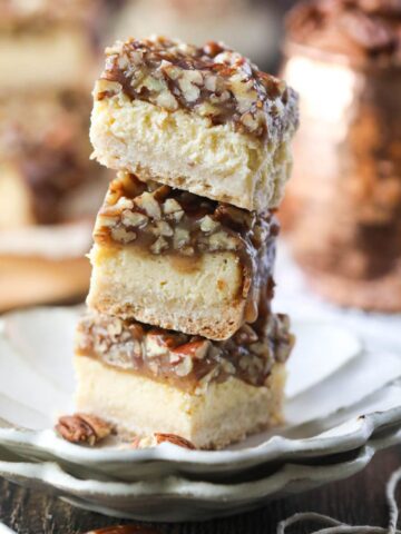 pecan pie cheesecake bars stacked on a white plate.