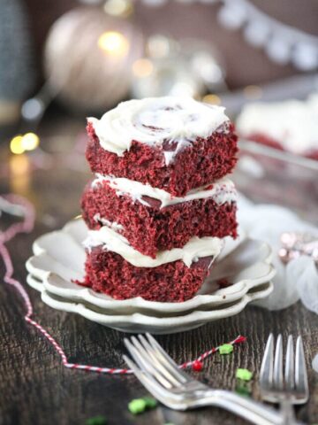 red velvet cinnamon rolls stacked on a white plate.