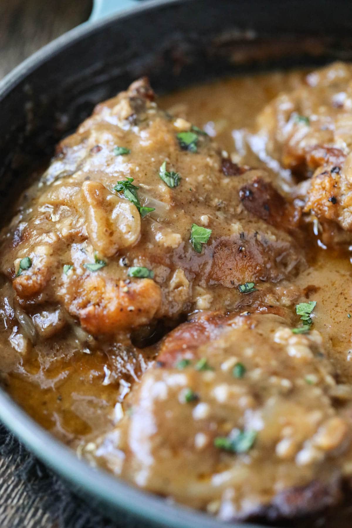 southern smothered chicken in a blue cast-iron skillet on a wooden surface.