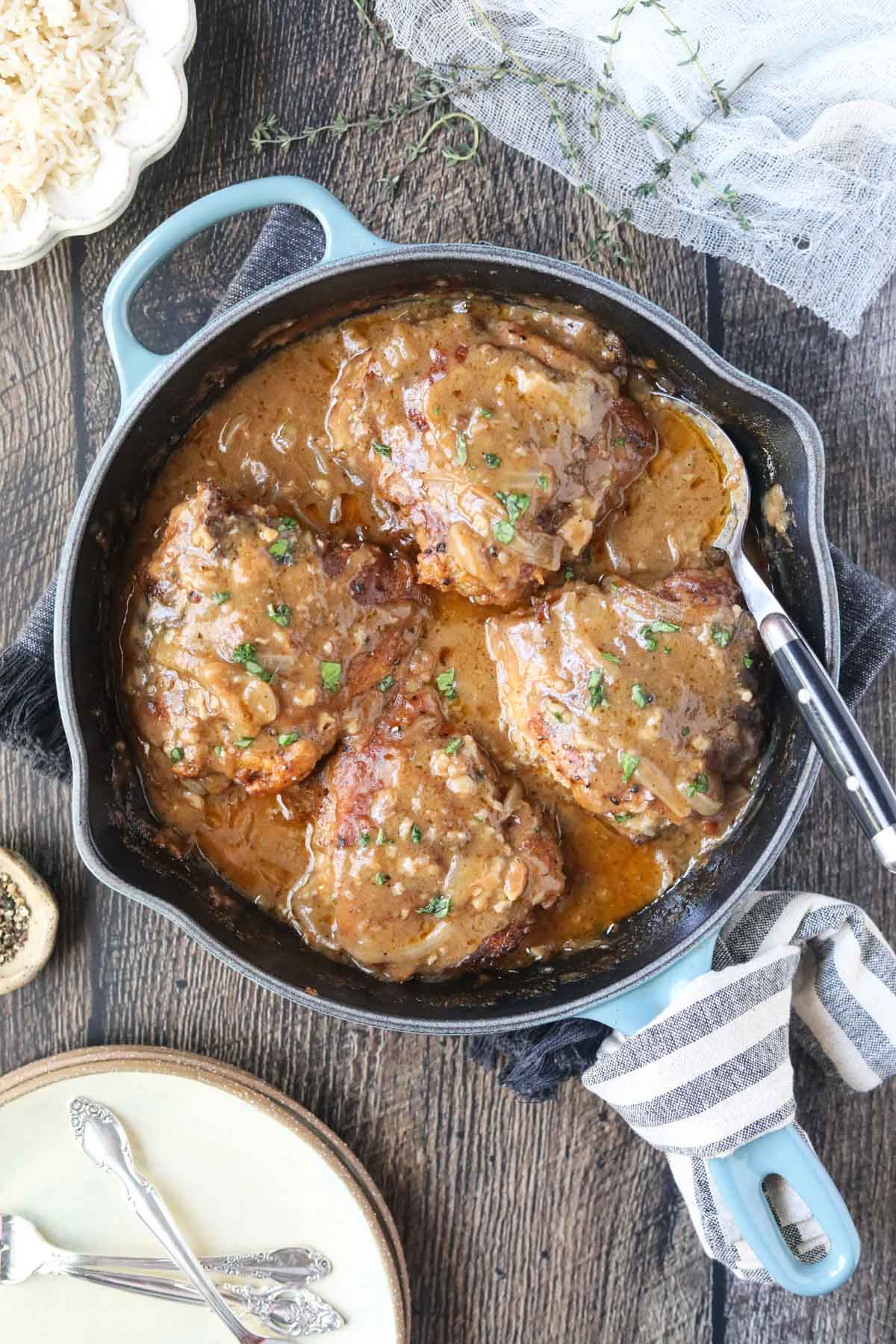 southern smothered chicken in a blue cast-iron skillet on a wooden surface.