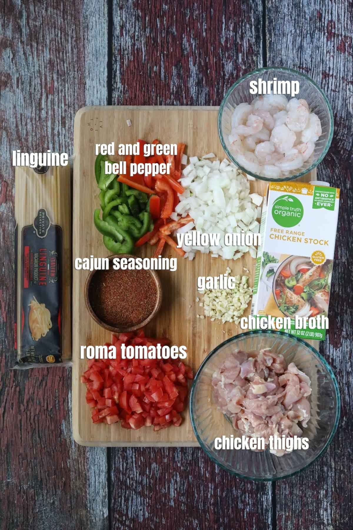 Ingredients for making Cajun jambalaya pasta spread out on a wooden cutting board.