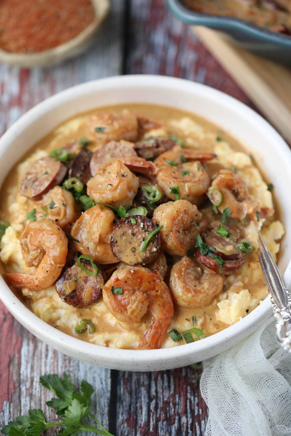 Cajun shrimp and grits in a lightbulb on a wooden surface.
