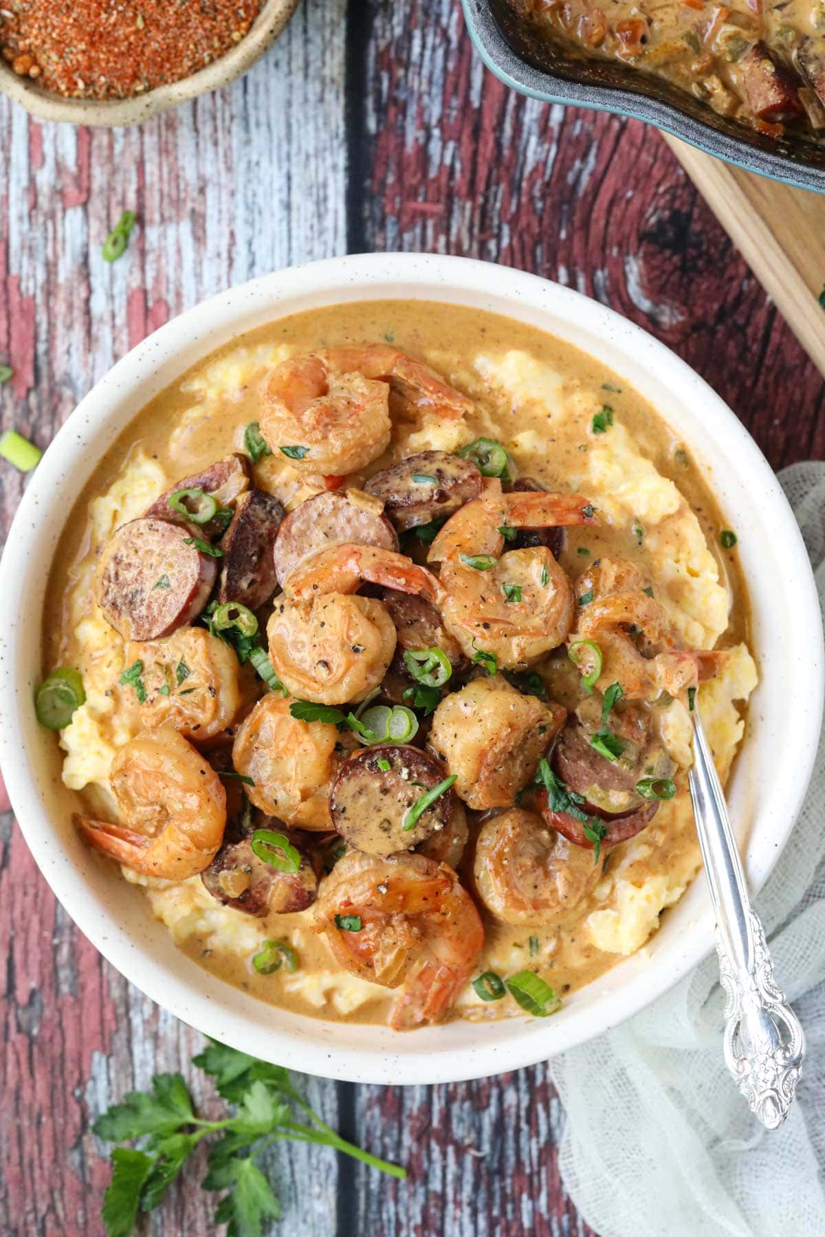 Cajun shrimp and grits in a lightbulb on a wooden surface.