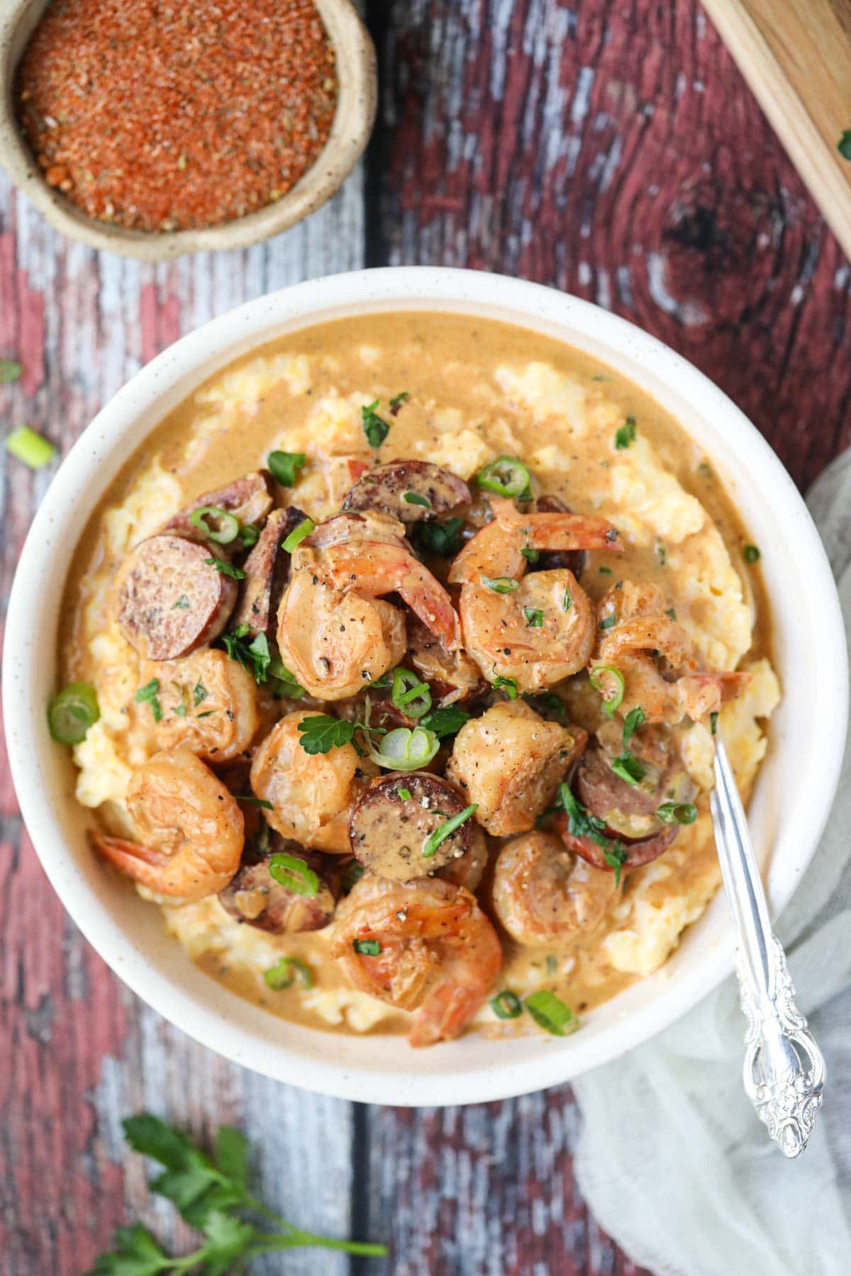 Cajun shrimp and grits in a lightbulb on a wooden surface.