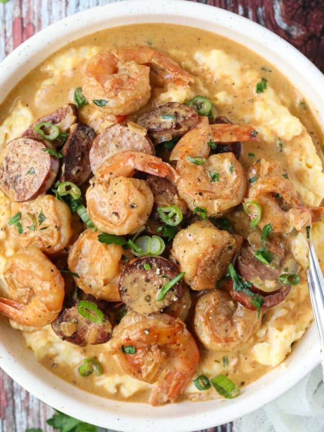 Cajun shrimp and grits in a lightbulb on a wooden surface.
