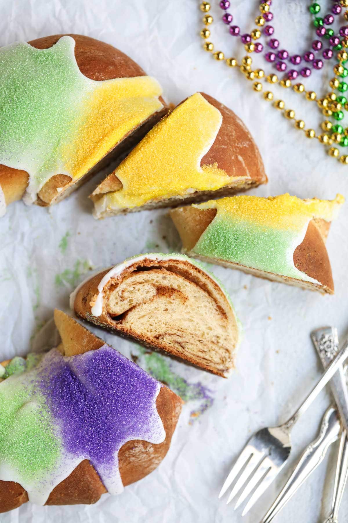 Sliced New Orleans king cake on a white surface.