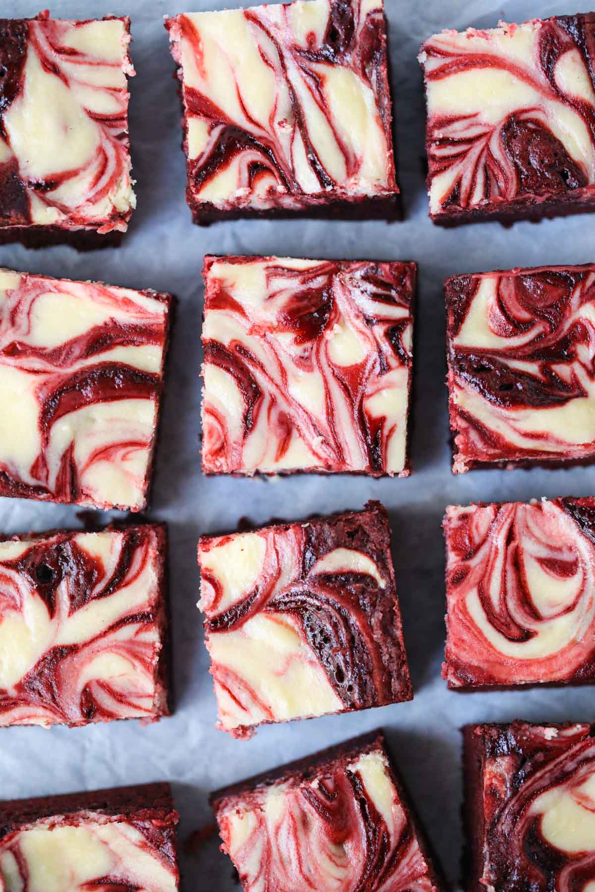 Red velvet cheesecake brownies arranged on parchment paper.