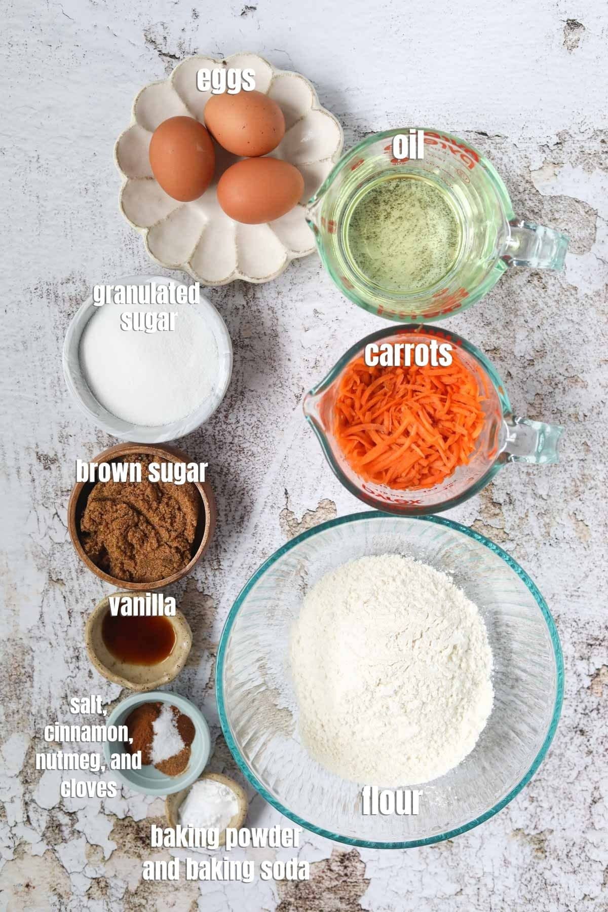 Carrot cake ingredients spread out on a white surface.