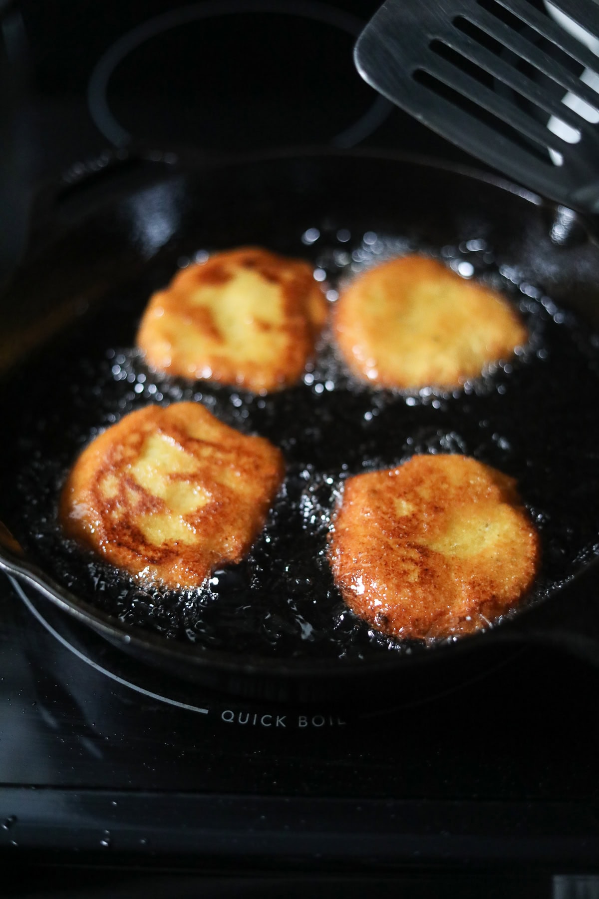 Hot water cornbread patties frying in hot oil.