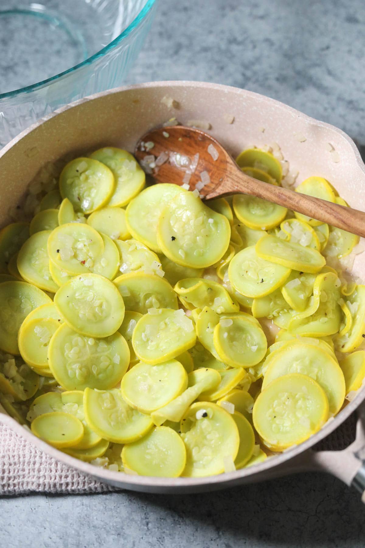 Yellow squash and onion sautéing in a skillet.