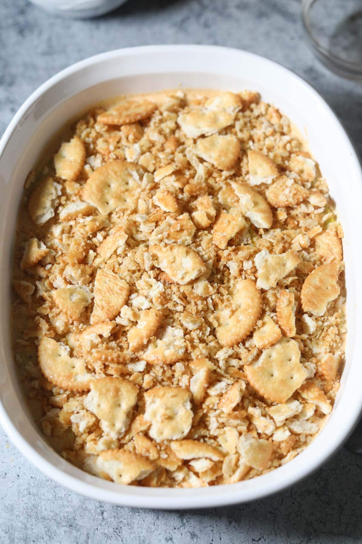 Southern squash casserole with cracker topping added in a baking dish before going into the oven.