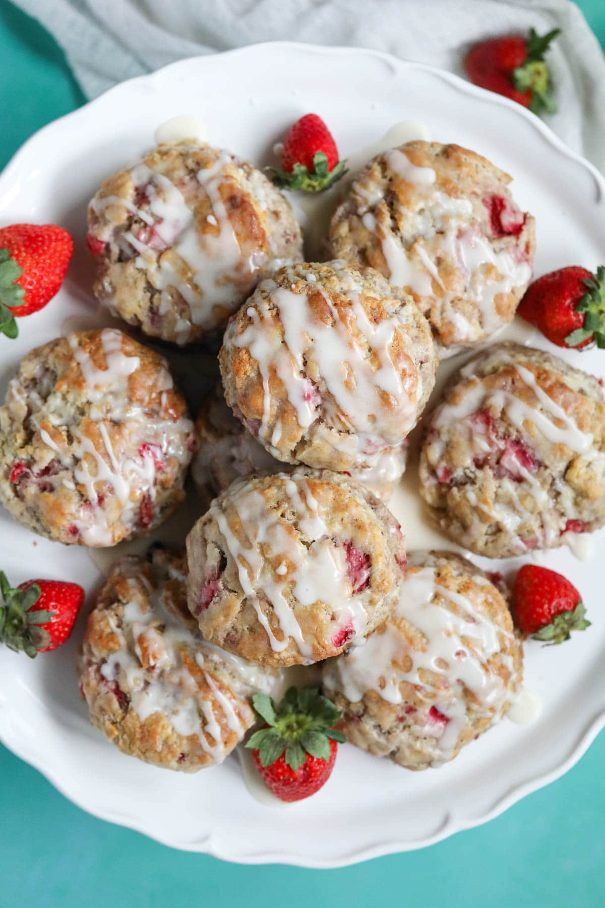 Strawberry biscuits on a white cake stand sitting on top of a blue surface.