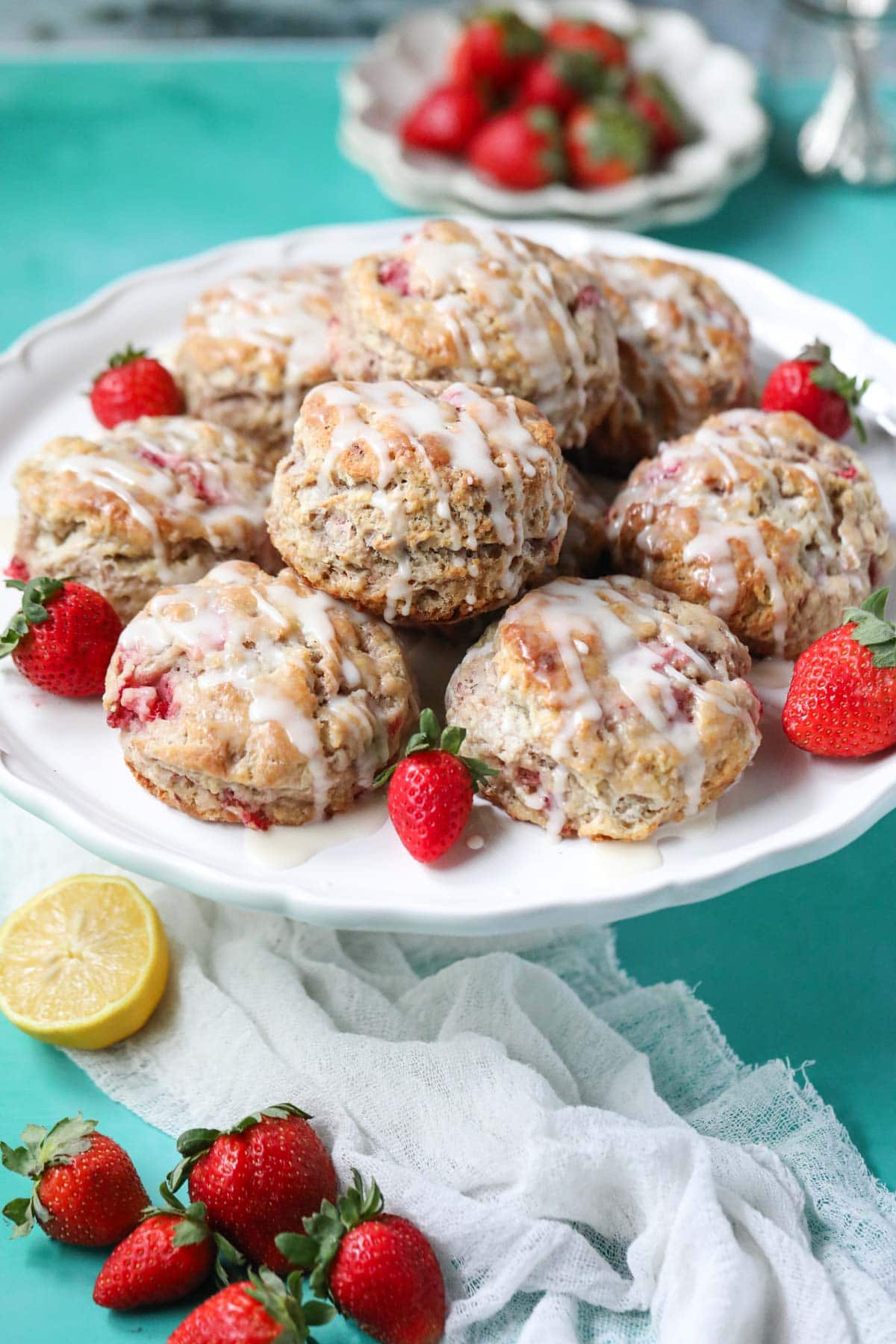 Strawberry biscuits on a white cake stand sitting on top of a blue surface.