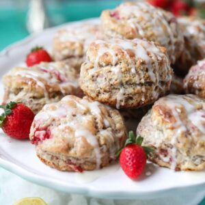 Strawberry biscuits on a white cake stand sitting on top of a blue surface.