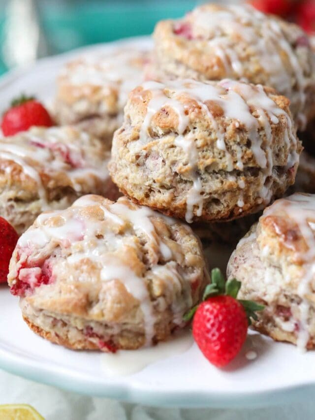 Strawberry biscuits on a white cake stand sitting on top of a blue surface.