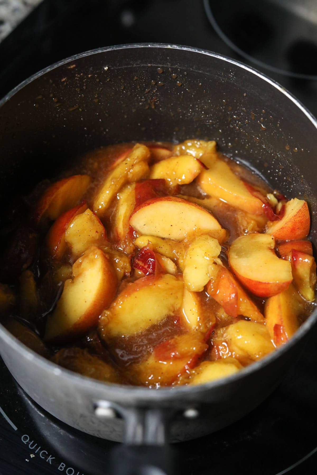 Peach filling for cobbler cooking in a saucepan.