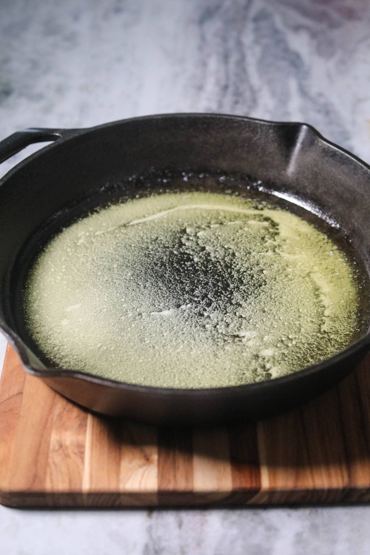 Melted butter in a cast iron skillet for peach cobbler.