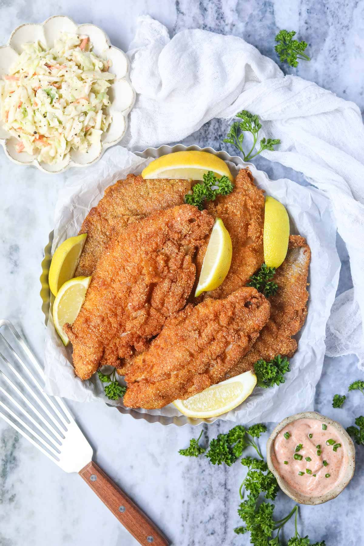 Southern fried catfish on a silver tray with Lemon slices.