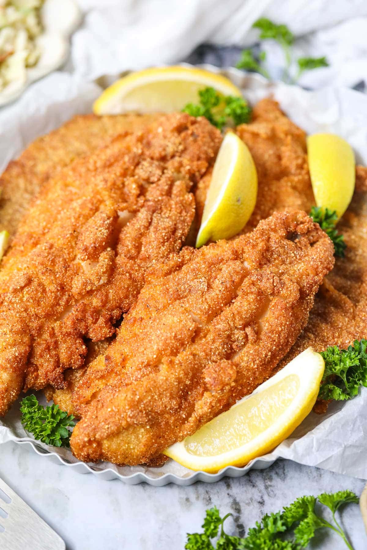 Southern fried catfish on a silver tray with Lemon slices.