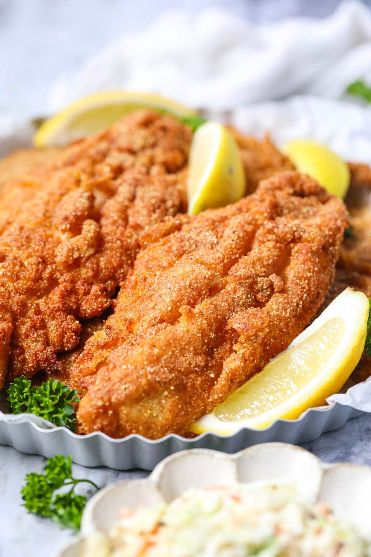 Southern fried catfish on a silver tray with Lemon slices.