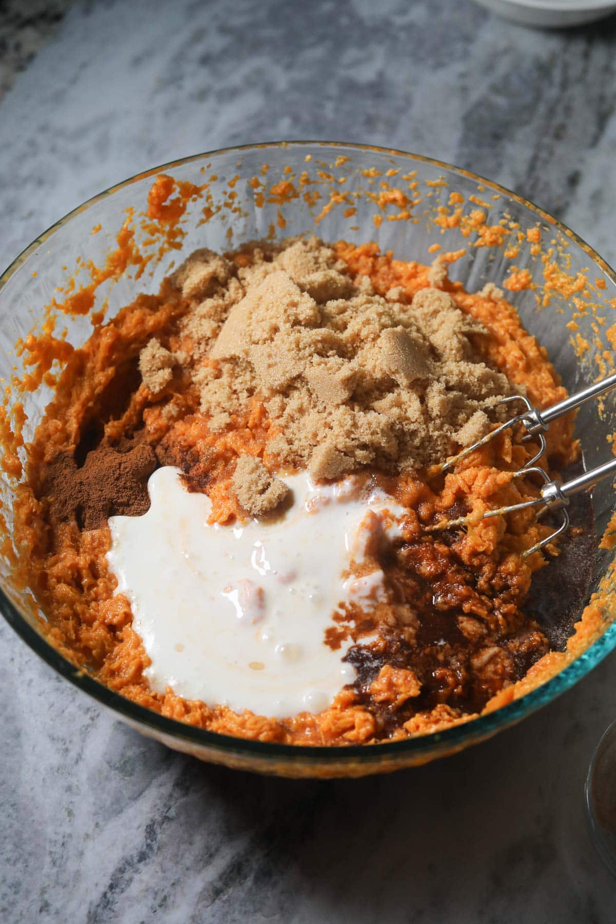 They're sweet potatoes and other ingredients in a large mixing bowl for sweet potato casserole.