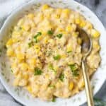 homemade creamed corn in a white bowl with a silver spoon.