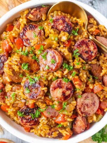 Cajun dirty rice with smoked sausage in a white bowl.