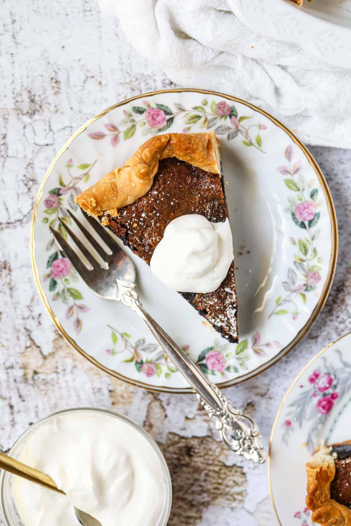 A slice of chocolate chess pie on a white dessert plate with a silver fork.