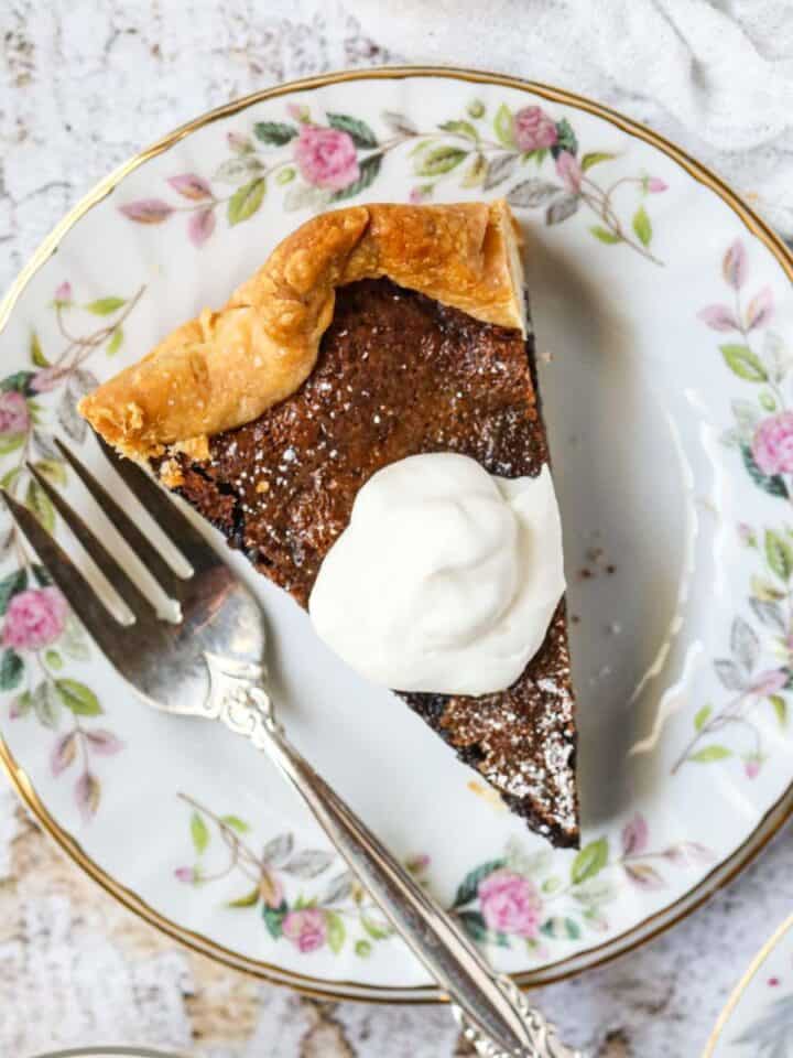 A slice of chocolate chess pie on a white dessert plate with a silver fork.