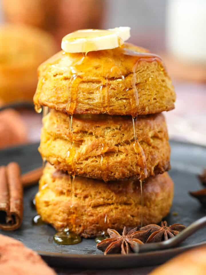 A stack of three sweet potato biscuits with honey and butter on a metal tray.
