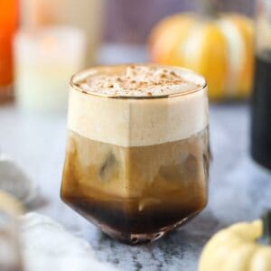 Pumpkin cream cold brew in a glass sitting on top of a gray marble surface.