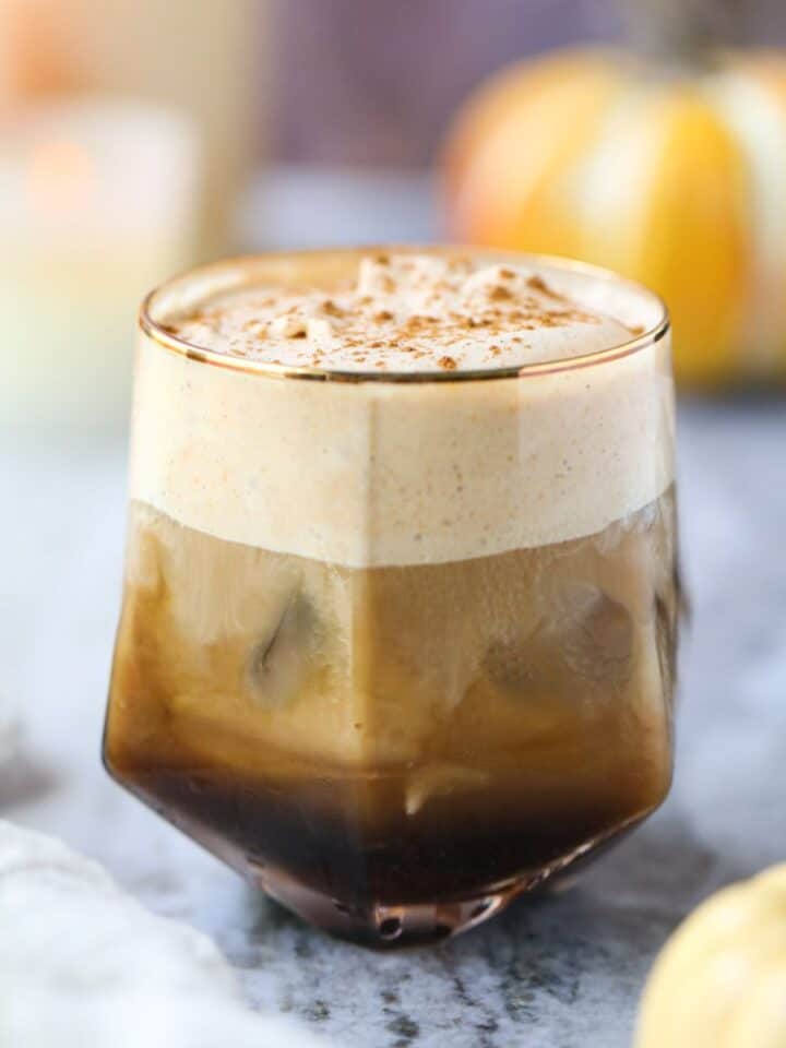 Pumpkin cream cold brew in a glass sitting on top of a gray marble surface.