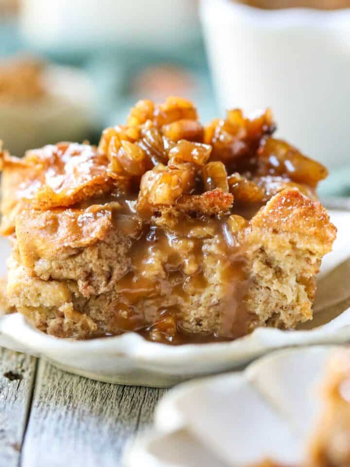 A serving of bread pudding with praline sauce on a white plate.