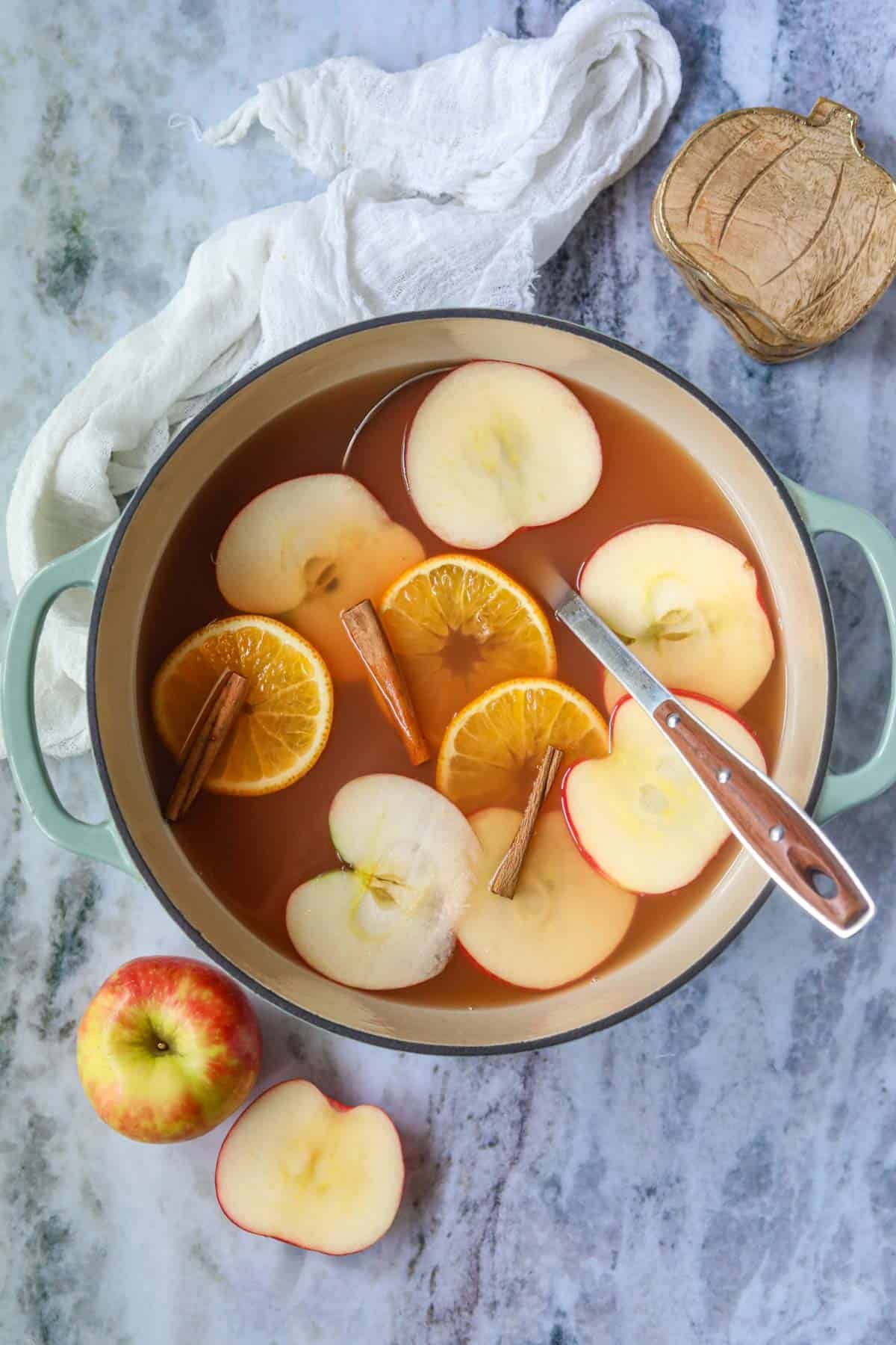 Homemade hot apple cider in a Dutch oven with a ladle.