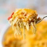 Easy chicken spaghetti with rotel on a serving spoon with a baking dish of chicken spaghetti in the background.