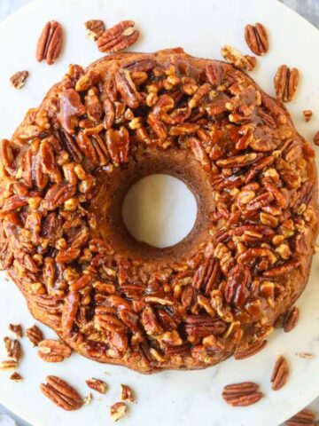 Pecan upside down cake on a white cake plate.