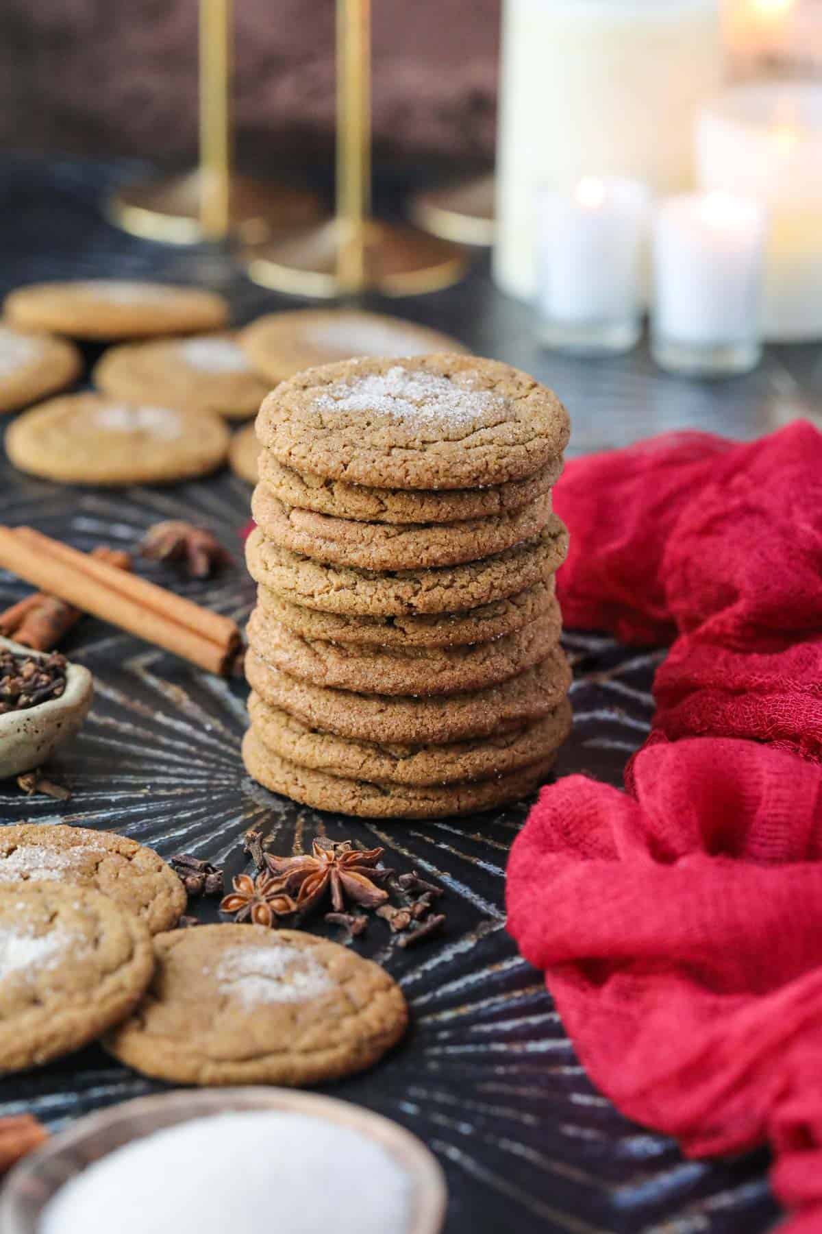 Chewy spiced molasses cookies stacked on a black surface.