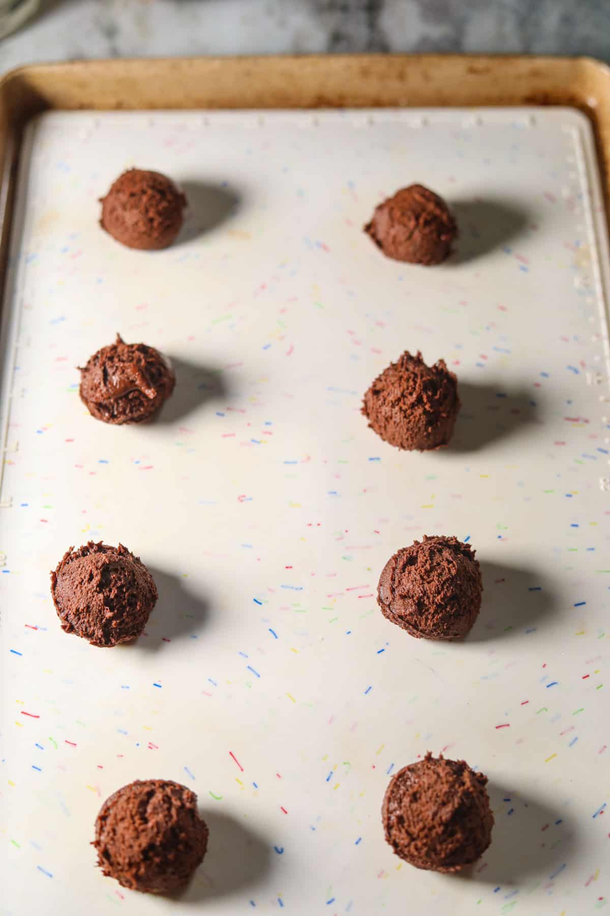 Peppermint bark cookie dough balls on a baking sheet before going in the oven.