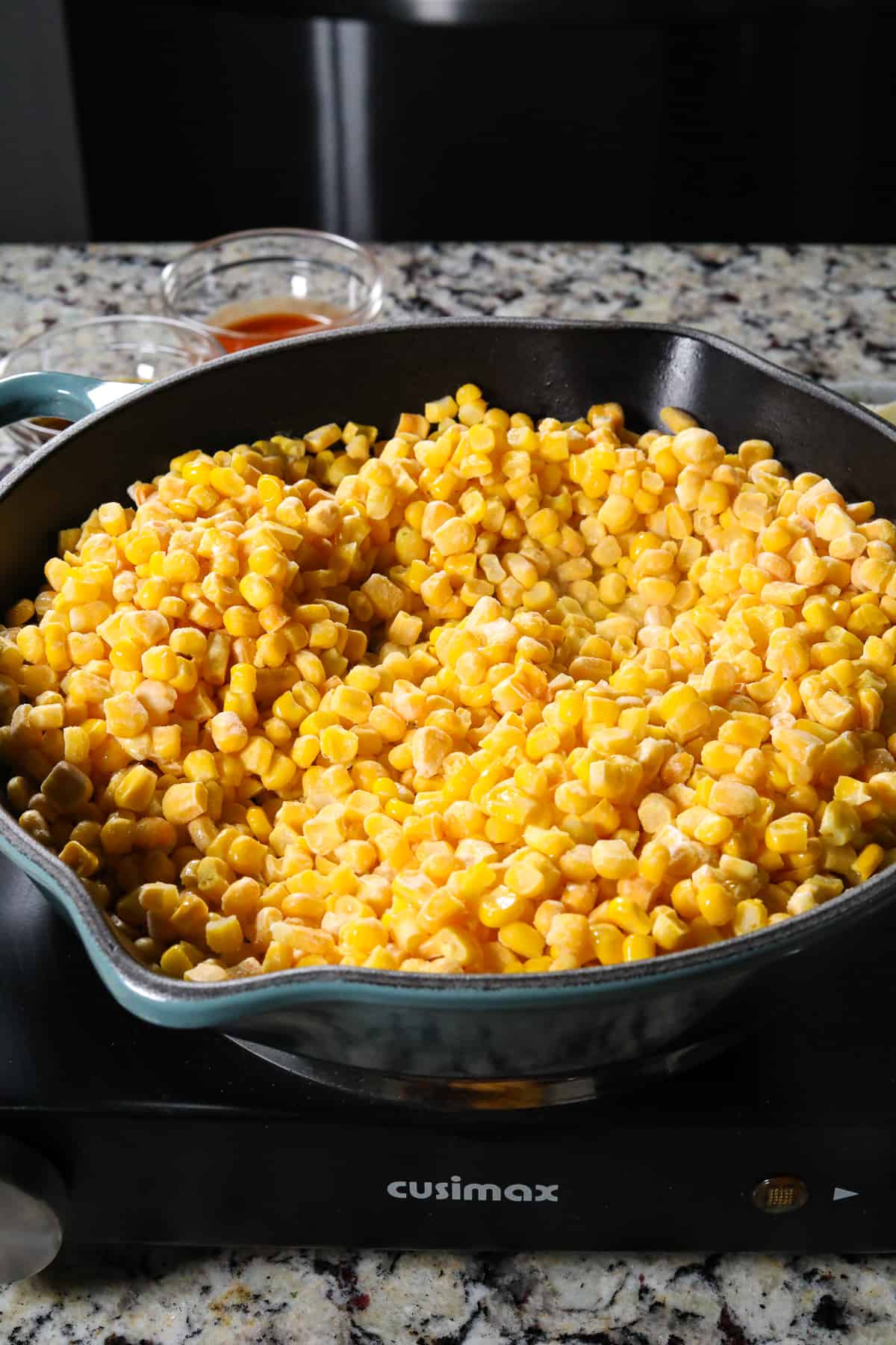 Frozen corn cooking and butter in a cast iron skillet.