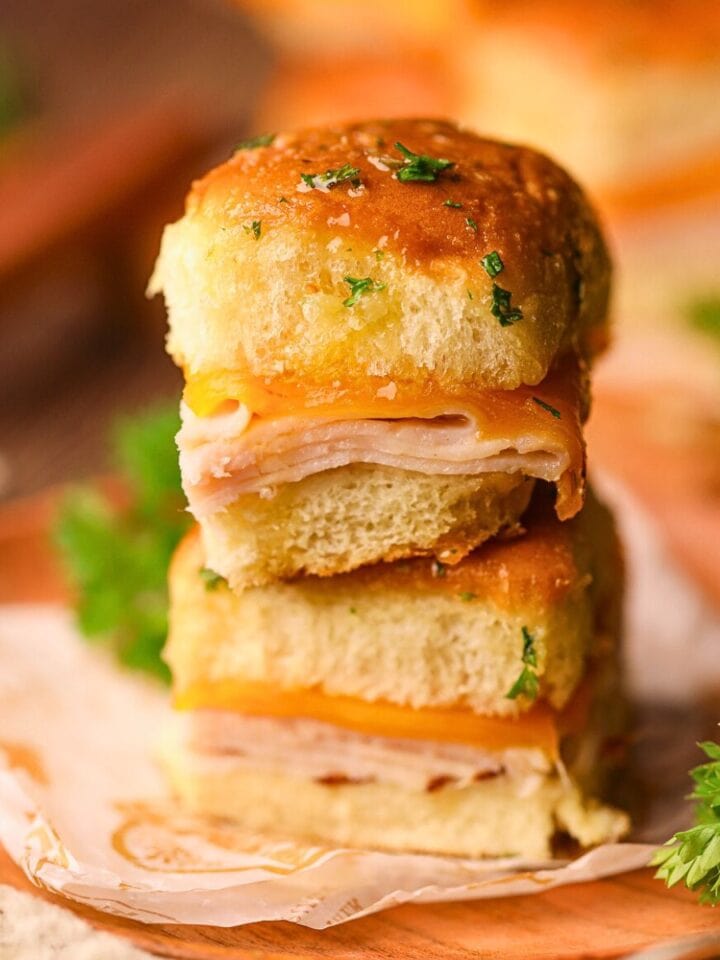turkey and cheese sliders stacked on a plate.