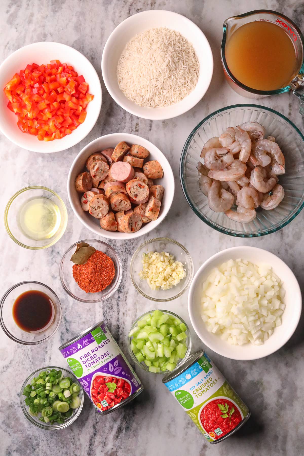 Ingredients for making shrimp and sausage jambalaya arranged in bowls on a table top.