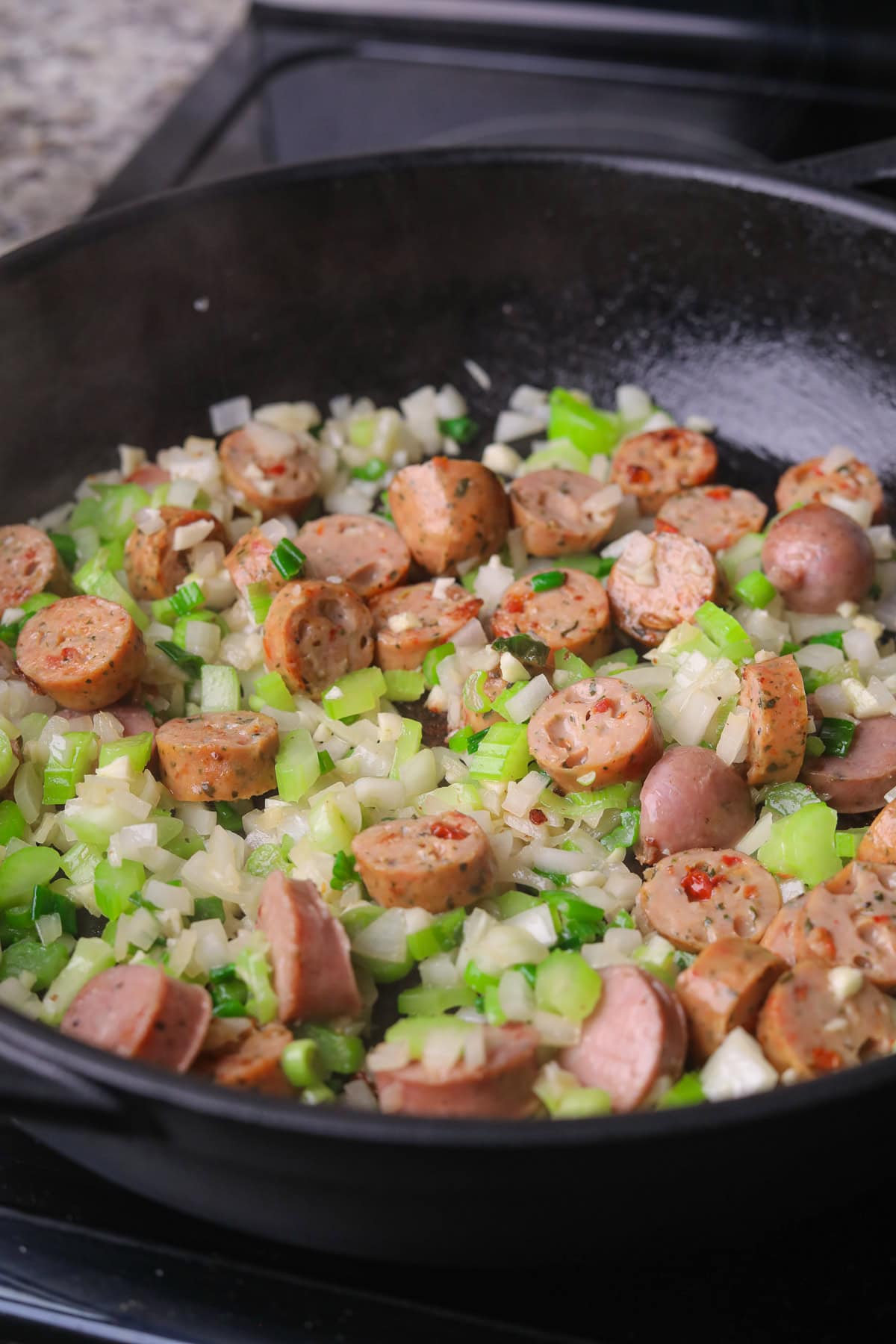 Sausage and chopped veggies cooking in a skillet.