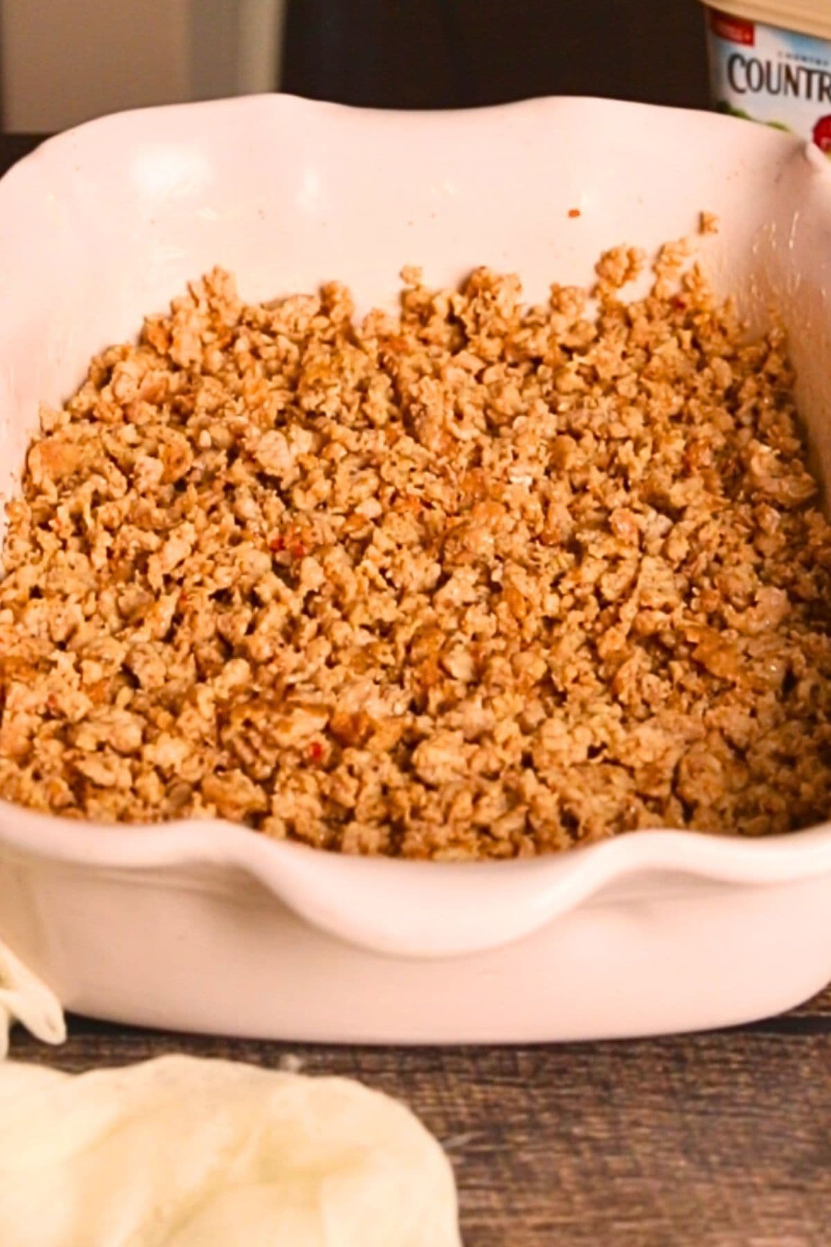 Sausage in the bottom of a baking dish for buttermilk biscuit breakfast casserole.